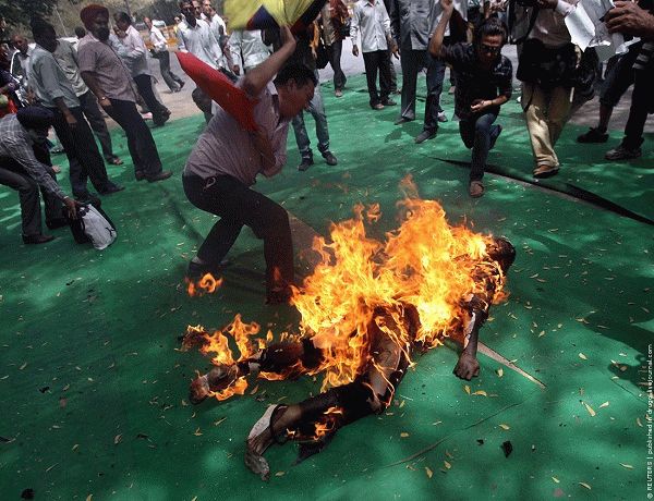 Tibetan exiles try to douse the flames from their comrade after he set himself on fire during a protest in New Delhi