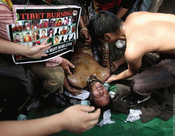 Tibetan exiles attend to their comrade after he set himself on fire during a protest in New Delhi